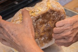 Testing doneness by tapping the bottom of the bread if it's hollow it's done.